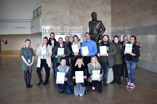 Students standing by the JL statue with their certificates