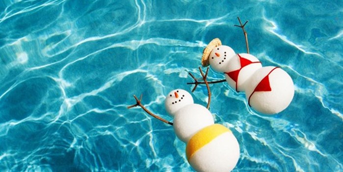 A snowman and woman swimming in a tropical pool