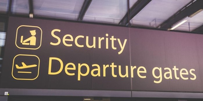 An airport sign showing the way to departure gates and security checkpoints.