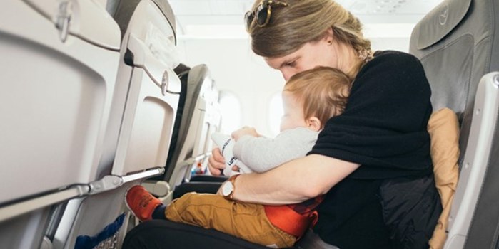 A mother soothing a young baby in the cabin of an aeroplane