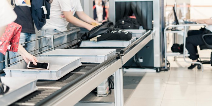 passengers at airport security placing their belongings into trays