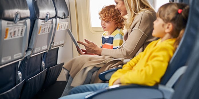 A mother with her two children on a flight, looking at a tablet device